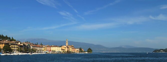 Trip Slowenien beliebte Urlaubsziele am Gardasee -  Mit einer Fläche von 370 km² ist der Gardasee der größte See Italiens. Es liegt am Fuße der Alpen und erstreckt sich über drei Staaten: Lombardei, Venetien und Trentino. Die maximale Tiefe des Sees beträgt 346 m, er hat eine längliche Form und sein nördliches Ende ist sehr schmal. Dort ist der See von den Bergen der Gruppo di Baldo umgeben. Du trittst aus deinem gemütlichen Hotelzimmer und es begrüßt dich die warme italienische Sonne. Du blickst auf den atemberaubenden Gardasee, der in zahlreichen Blautönen schimmert - von tiefem Dunkelblau bis zu funkelndem Türkis. Majestätische Berge umgeben dich, während die Brise sanft deine Haut streichelt und der Duft von blühenden Zitronenbäumen deine Nase kitzelt. Du schlenderst die malerischen, engen Gassen entlang, vorbei an farbenfrohen, blumengeschmückten Häusern. Vereinzelt unterbricht das fröhliche Lachen der Einheimischen die friedvolle Stille. Du fühlst dich wie in einem Traum, der nicht enden will. Jeder Schritt führt dich zu neuen Entdeckungen und Abenteuern. Du probierst die köstliche italienische Küche mit ihren frischen Zutaten und verführerischen Aromen. Die Sonne geht langsam unter und taucht den Himmel in ein leuchtendes Orange-rot - ein spektakulärer Anblick.